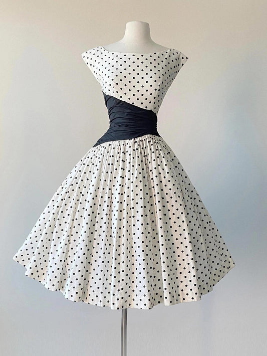 Cap Sleeve Vintage 50s Polka Dot Swing Dress with Black Asymmetrical Waist Panel - DollyGown